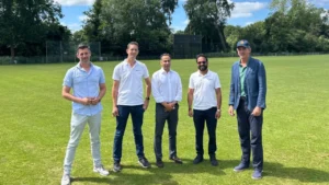 Vineeth Kichilu, CEO of fusionAIx, KNCB Board Member Rashid Shah, and representatives from fusionAIx and the Royal Dutch Cricket Association (KNCB) stand on a cricket field after agreeing to a sponsorship deal.