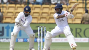 An India batsman plays a shot during a Test match against Sri Lanka as the wicketkeeper watches behind the stumps in the India vs Sri Lanka Test series.
