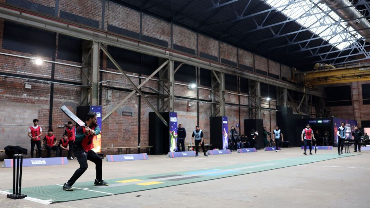 Players compete during the launch event for an indoor tape ball cricket tournament, showcasing batting and fielding action inside an indoor sports venue.