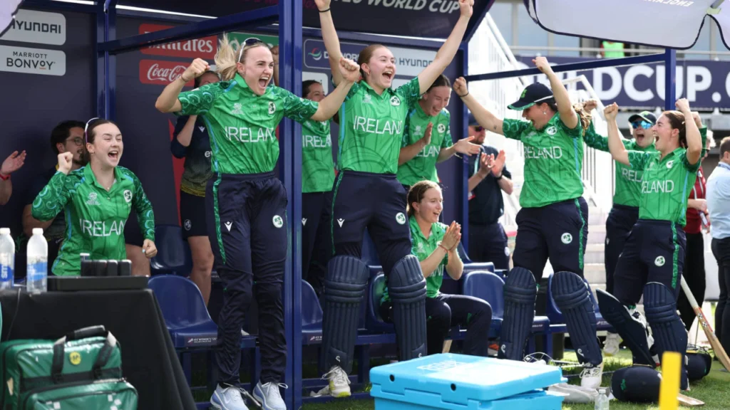 Ireland women's cricket team celebrates enthusiastically in the dugout during an international cricket match after a key moment.