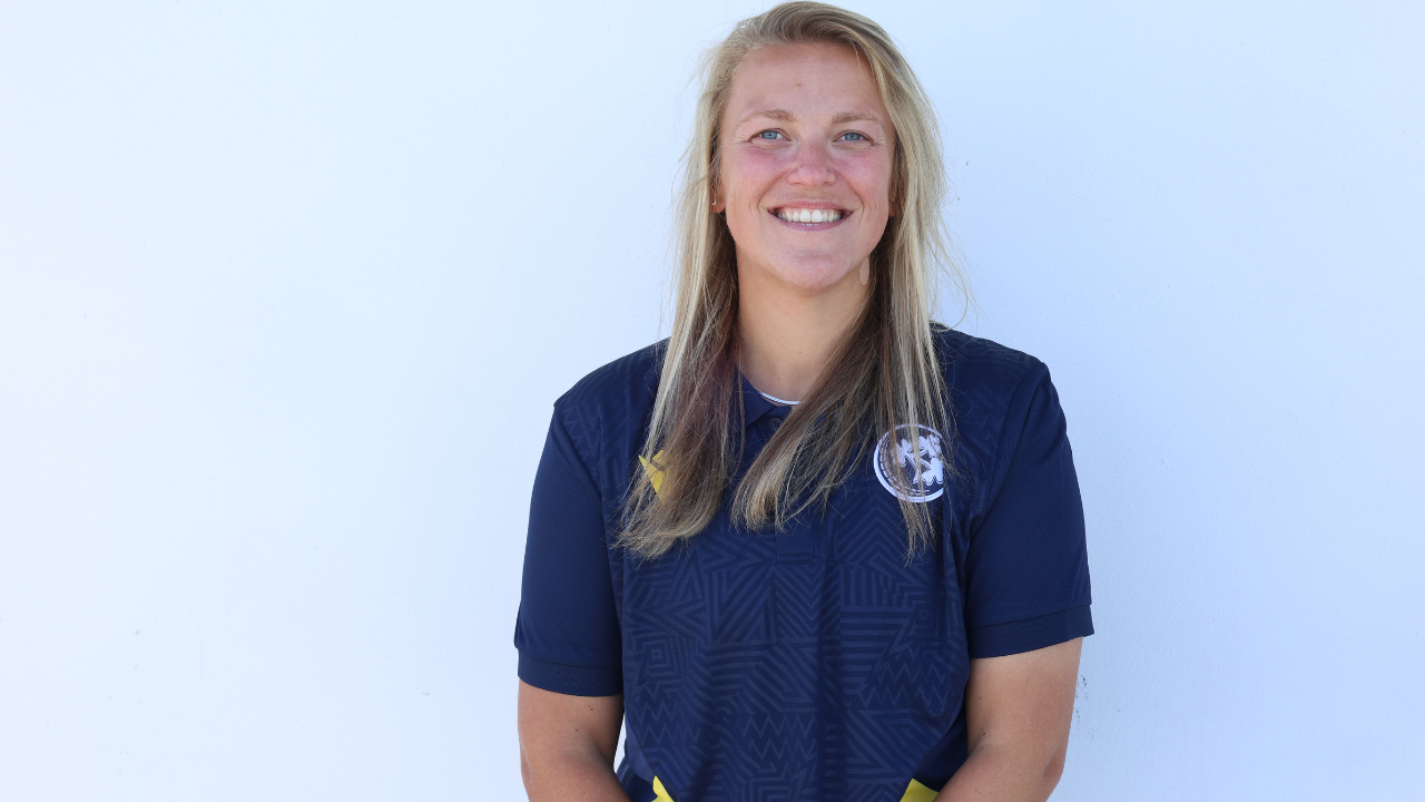 Portrait of Lauren Rowles smiling in a navy team polo shirt against a white background.