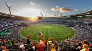 A packed crowd fills the Melbourne Cricket Ground (MCG) during a cricket match, with a panoramic view of the stadium at sunset.
