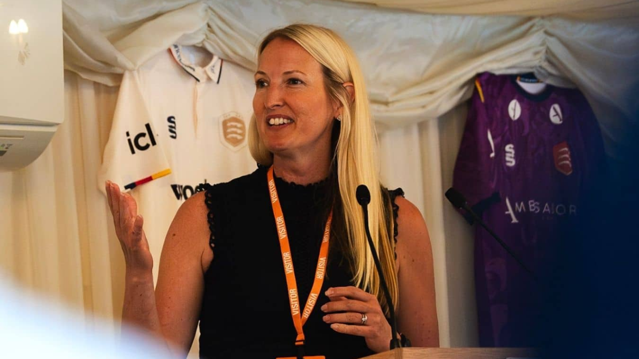 Rachel Lewis speaks at an Essex Cricket event following her appointment as the club's new Chair, with Essex Cricket shirts displayed in the background.