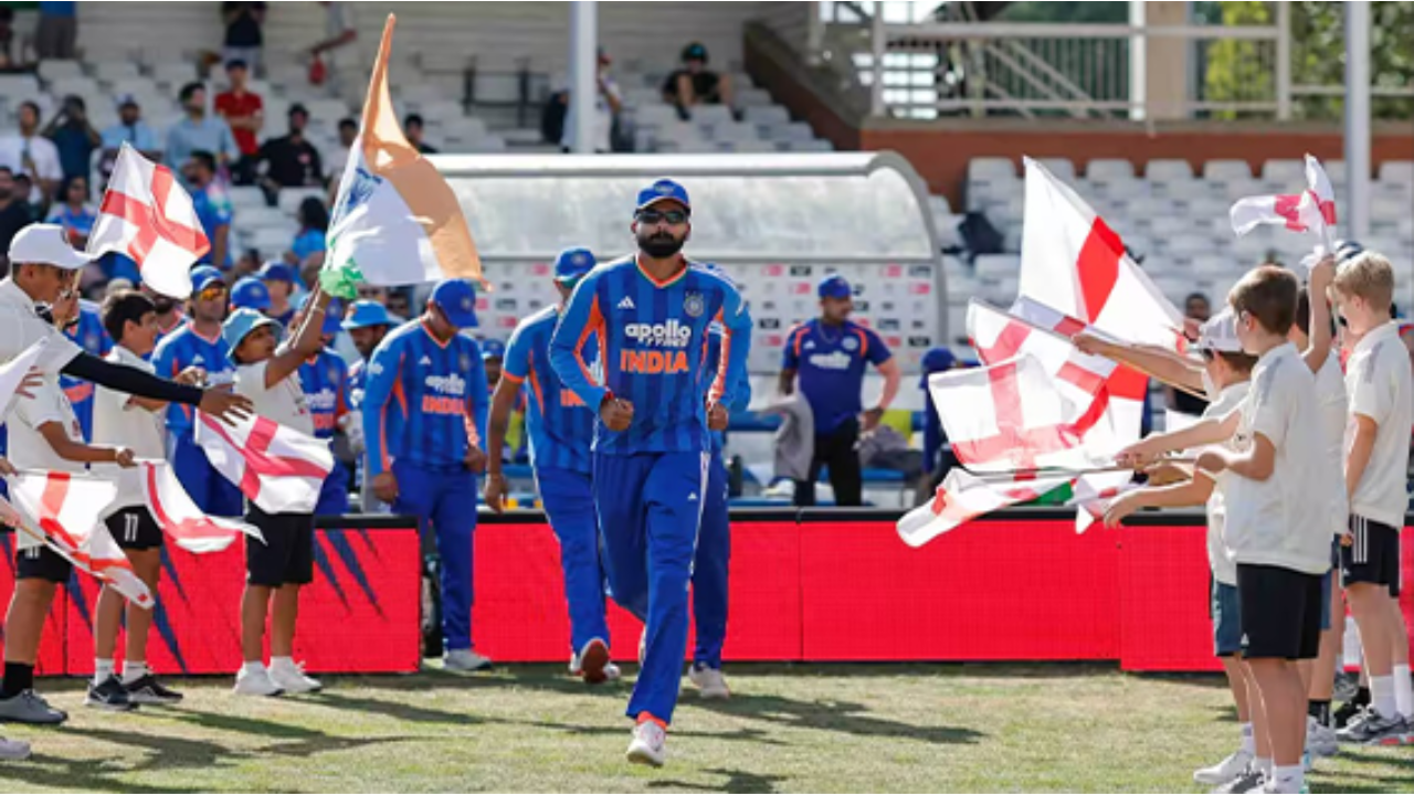 Shreyas Iyer leads the India T20 cricket team onto the field as captain before an international match, with teammates and fans waving flags.