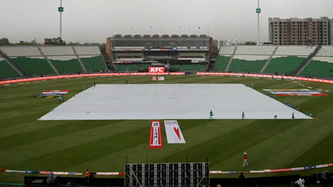 Gaddafi Stadium in Lahore with the cricket pitch covered during wet weather.