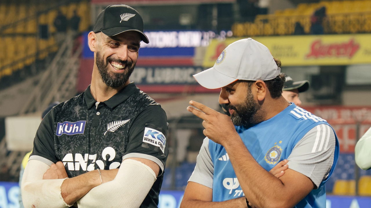 Rohit Sharma and Daryl Mitchell share a light moment during an India-New Zealand cricket match.