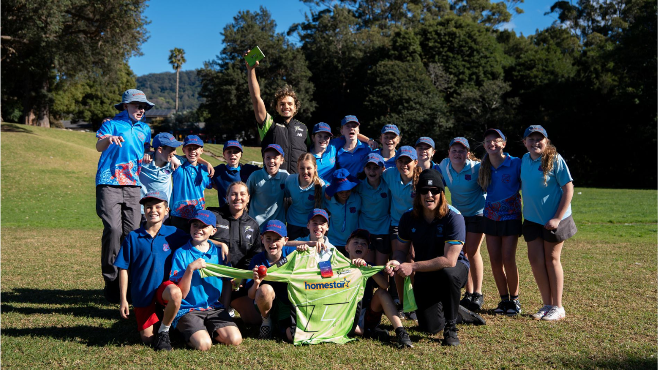 Australian cricketers Sam Konstas and Anika Learoyd pose with children during a community cricket clinic, promoting youth participation in cricket.