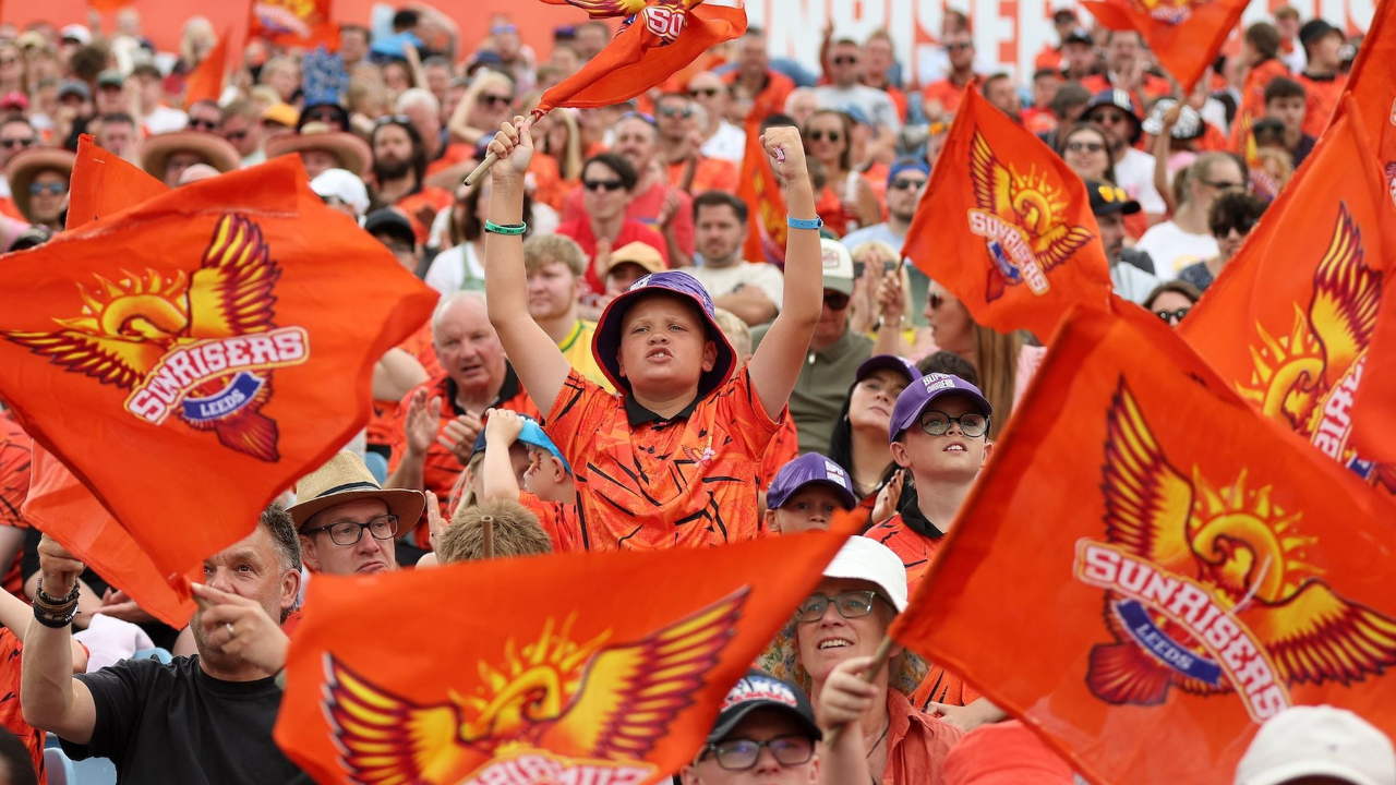SunRisers Leeds fans celebrate at Headingley, waving orange team flags in the stands.