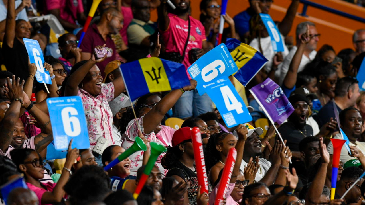 CPL cricket fans cheering in the stands while waving a Barbados Tridents flag