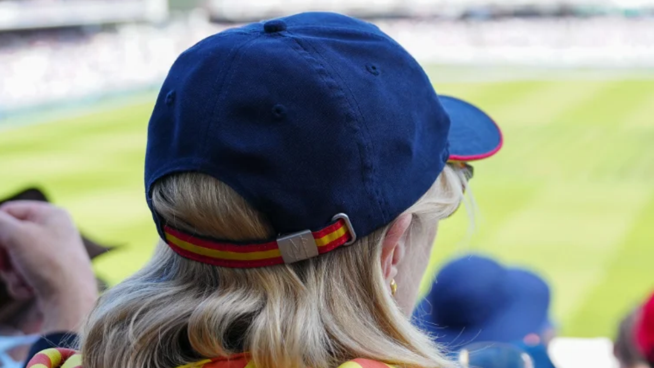 Cricket spectator wearing a blue cap with MCC logo while watching a match at Lord's Cricket Ground