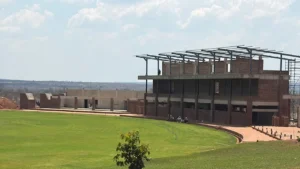 Mosi-oa-Tunya International Cricket Stadium in Victoria Falls, Zimbabwe, showing the green cricket ground and stadium pavilion under construction.