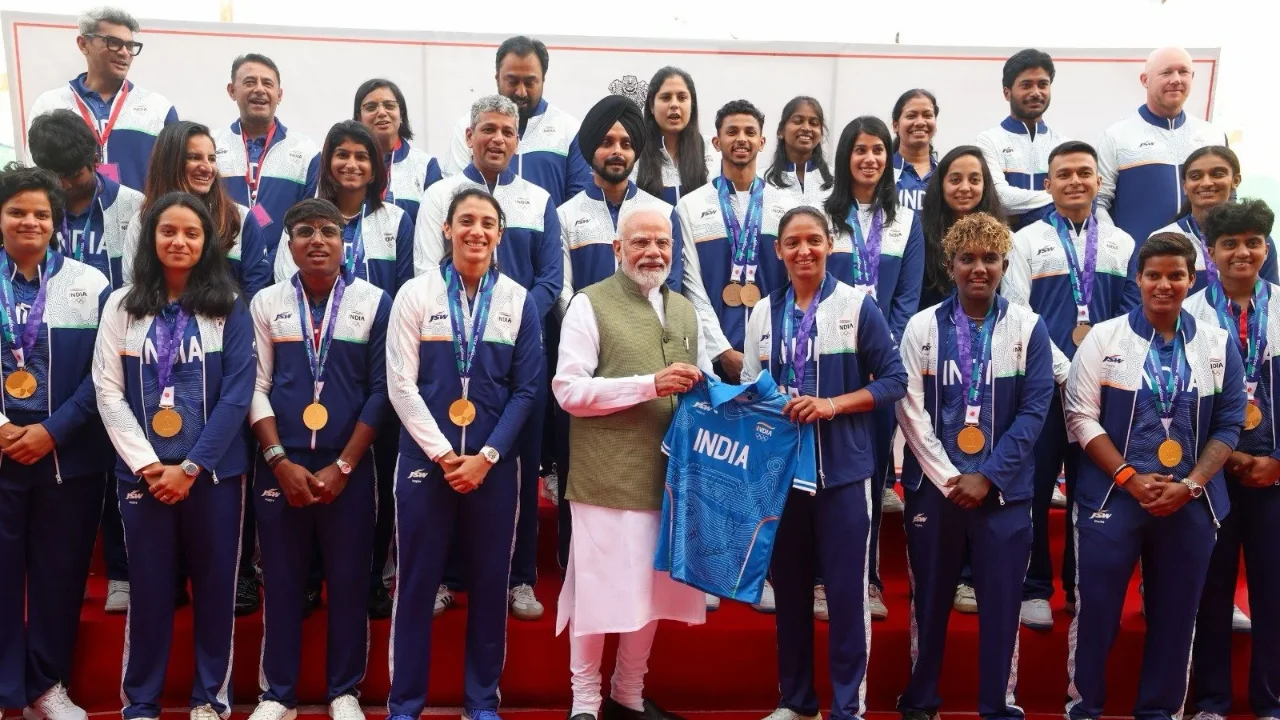 Indian Prime Minister Narendra Modi honours India's Asian Games medallists, posing with athletes wearing medals and holding a Team India jersey during a felicitation ceremony.