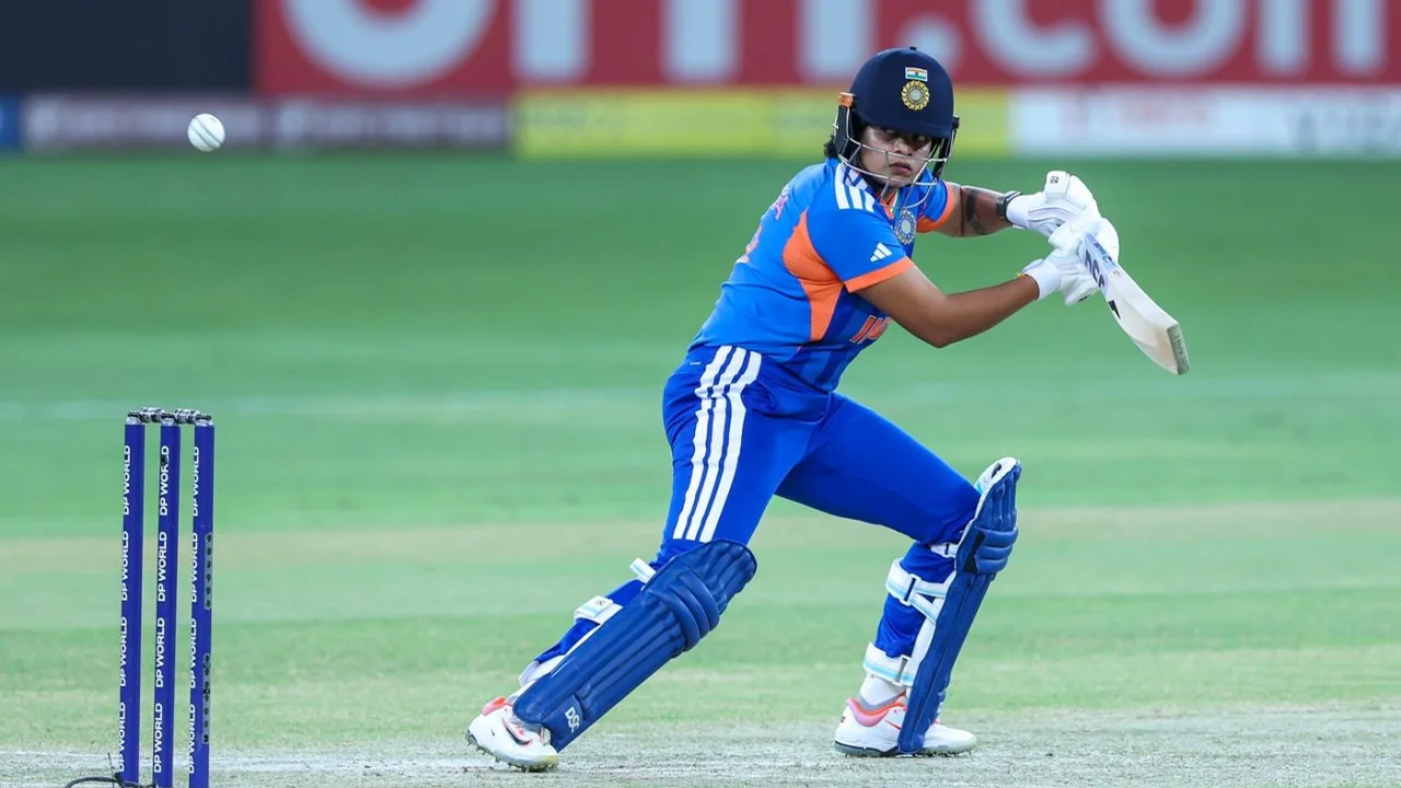 Indian women's cricket team batter Shafali Verma plays a shot during a match, wearing India's blue jersey and batting helmet.