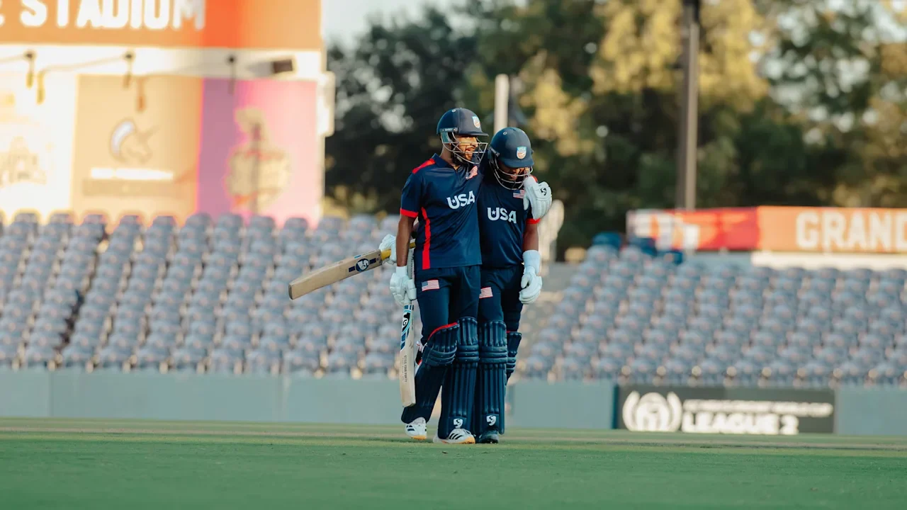 Two USA cricketers walk together on the field after defeating Namibia in an ICC Cricket World Cup League 2 match.